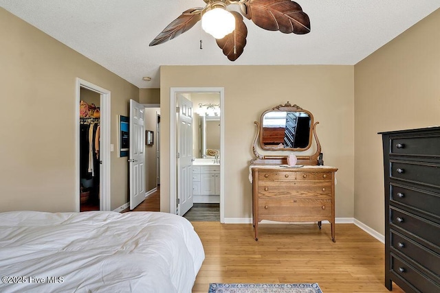 1005 Bellmark Ct, Leland, NC 28451 - bedroom with light wood-type flooring, baseboards, ensuite bath, a walk in closet, and ceiling fan