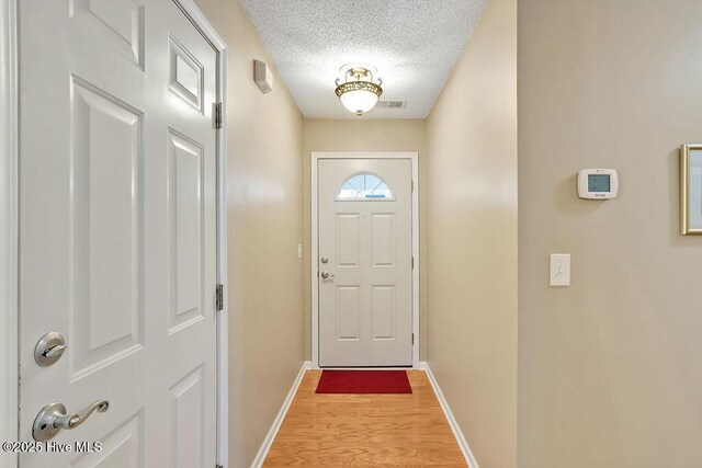1005 Bellmark Ct, Leland, NC 28451 - doorway to outside featuring a textured ceiling, light wood-style flooring, and baseboards