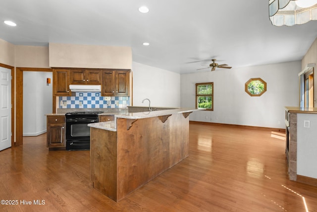 163 Middleton Dr, Hertford, NC 27944 - kitchen with dark wood-style floors, under cabinet range hood, a kitchen breakfast bar, ceiling fan, and black electric range