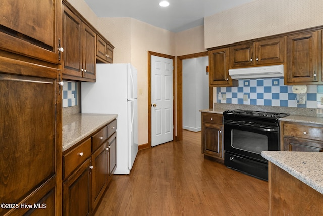 163 Middleton Dr, Hertford, NC 27944 - kitchen with decorative backsplash, black gas stove, freestanding refrigerator, under cabinet range hood, and dark wood-type flooring