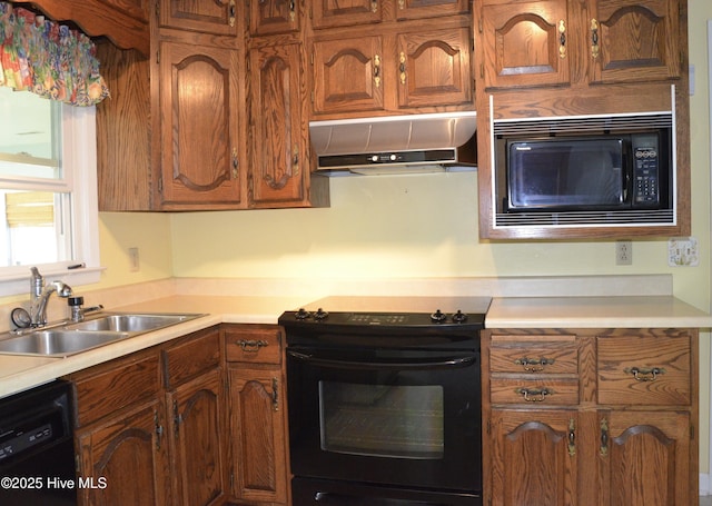 101 N Channel Haven Dr, Wilmington, NC 28409 - kitchen with under cabinet range hood, black appliances, a sink, brown cabinetry, and light countertops