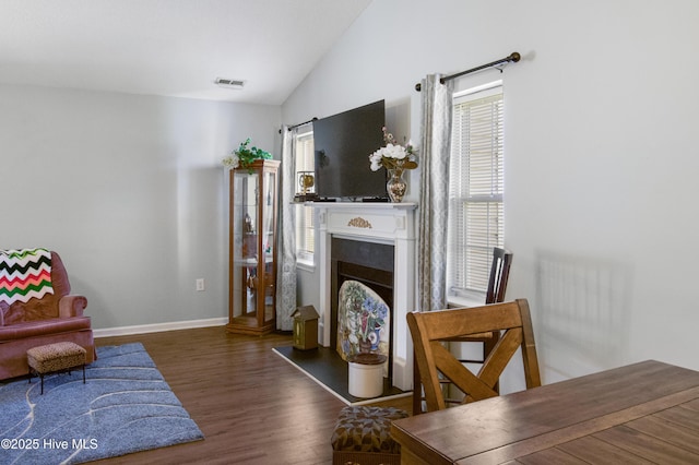 living area with a fireplace, wood finished floors, visible vents, baseboards, and lofted ceiling