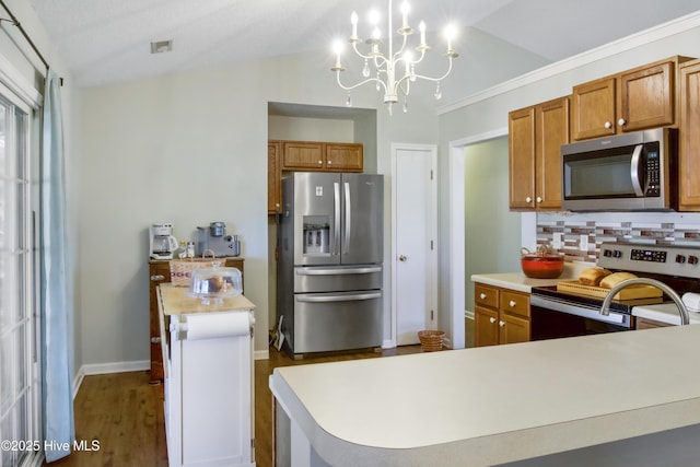kitchen with brown cabinets, a notable chandelier, backsplash, light countertops, and appliances with stainless steel finishes
