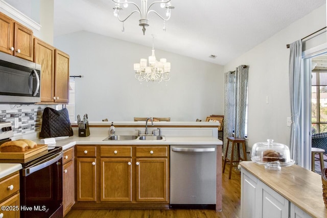 kitchen with stainless steel appliances, a notable chandelier, lofted ceiling, and a sink