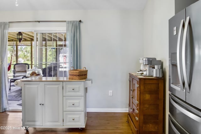 interior space featuring dark wood-type flooring, white cabinets, stainless steel fridge, and baseboards