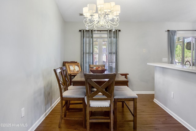 dining room featuring a wealth of natural light, wood finished floors, a notable chandelier, and baseboards