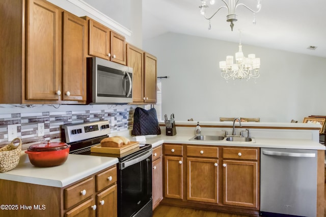 kitchen featuring a sink, stainless steel appliances, a notable chandelier, a peninsula, and lofted ceiling