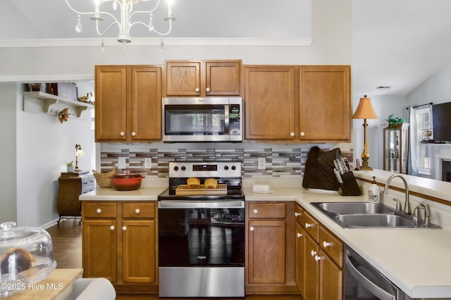 kitchen with tasteful backsplash, stainless steel appliances, light countertops, a sink, and a peninsula