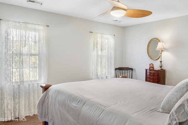 bedroom featuring wood finished floors, ceiling fan, visible vents, and multiple windows