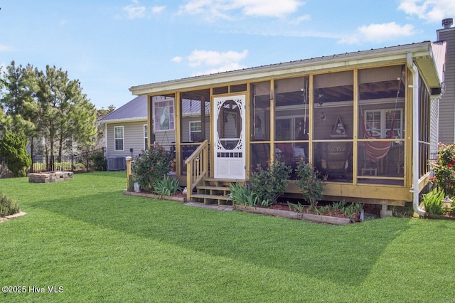 rear view of property featuring central AC unit, metal roof, a sunroom, and a lawn