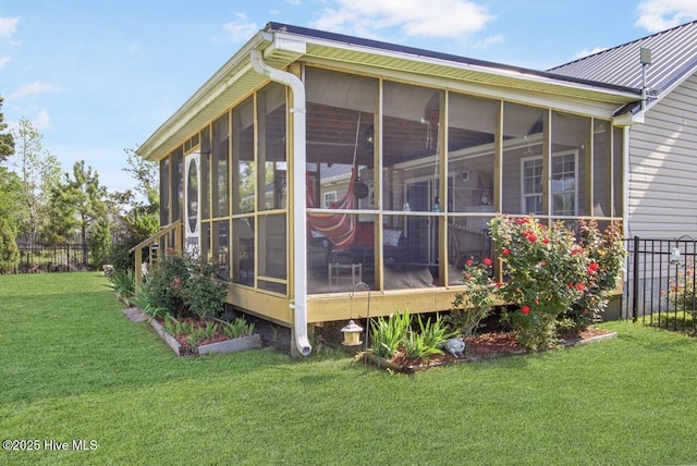 view of property exterior featuring fence, a yard, and a sunroom