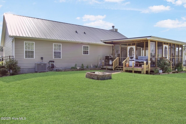back of house featuring a fire pit, cooling unit, a yard, and a sunroom