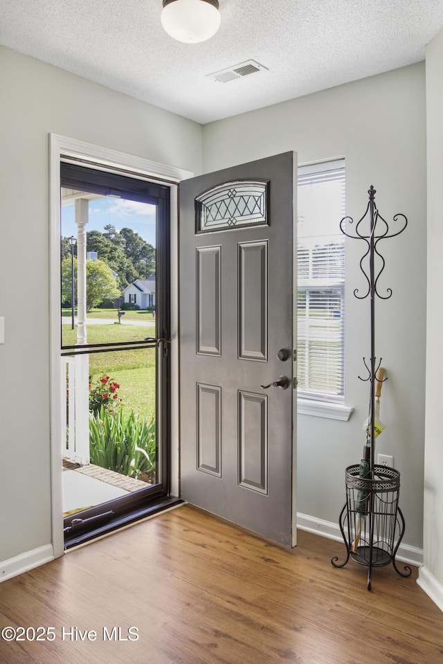 foyer with visible vents, baseboards, wood finished floors, and plenty of natural light