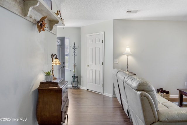 living room featuring a textured ceiling, visible vents, baseboards, and dark wood-type flooring