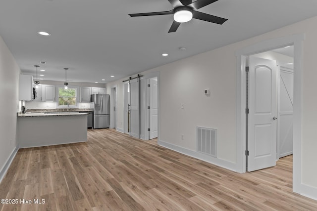 822 N Lord St, Southport, NC 28461 - unfurnished living room with visible vents, ceiling fan, light wood finished floors, and a barn door