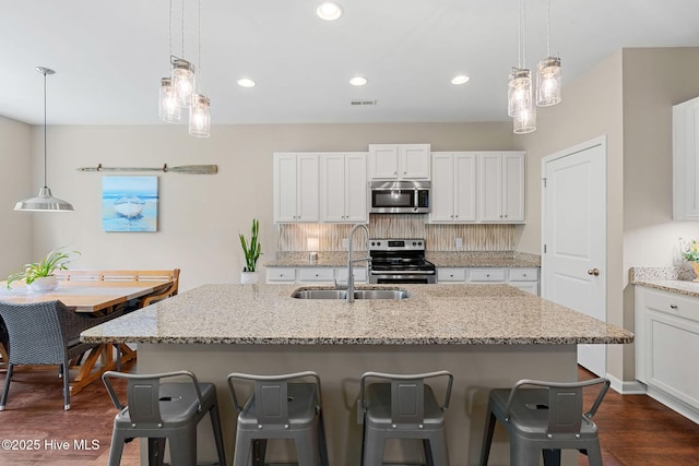 1699 Haldon Ln SE, Bolivia, NC 28422 - kitchen with white cabinets, a breakfast bar, a sink, stainless steel appliances, and visible vents