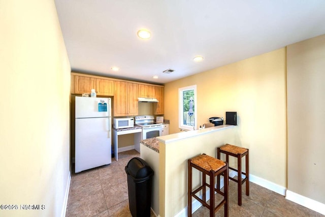 1699 Haldon Ln SE, Bolivia, NC 28422 - kitchen with white appliances, a peninsula, a kitchen bar, under cabinet range hood, and visible vents