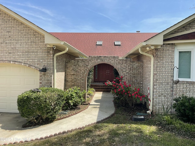 995 Chadwick Shores Dr, Sneads Ferry, NC 28460 - view of exterior entry with an attached garage, brick siding, and a shingled roof