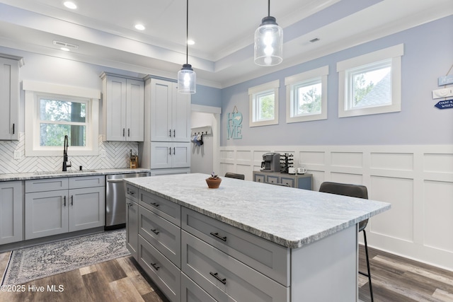 kitchen featuring a sink, a decorative wall, gray cabinets, tasteful backsplash, and stainless steel dishwasher