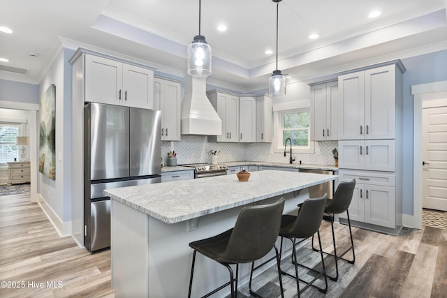 kitchen featuring decorative backsplash, ornamental molding, stainless steel appliances, and visible vents