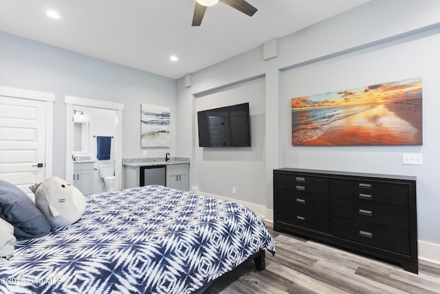 bedroom with refrigerator, light wood-type flooring, recessed lighting, connected bathroom, and a sink