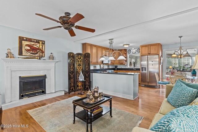 1613 E Pelican Dr, Oak Island, NC 28465 - living room with ceiling fan with notable chandelier, a tiled fireplace, and light wood finished floors