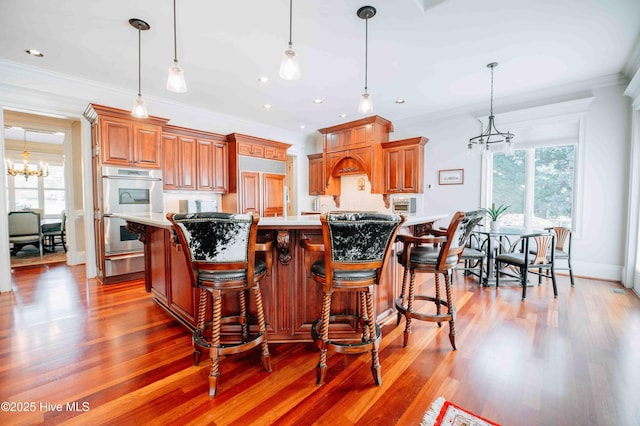 kitchen featuring stainless steel double oven, paneled refrigerator, light countertops, a warming drawer, and a notable chandelier
