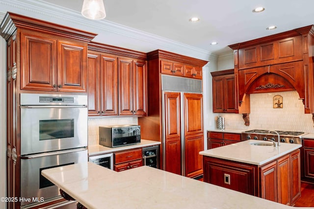 kitchen featuring a center island with sink, stainless steel double oven, paneled fridge, light countertops, and tasteful backsplash
