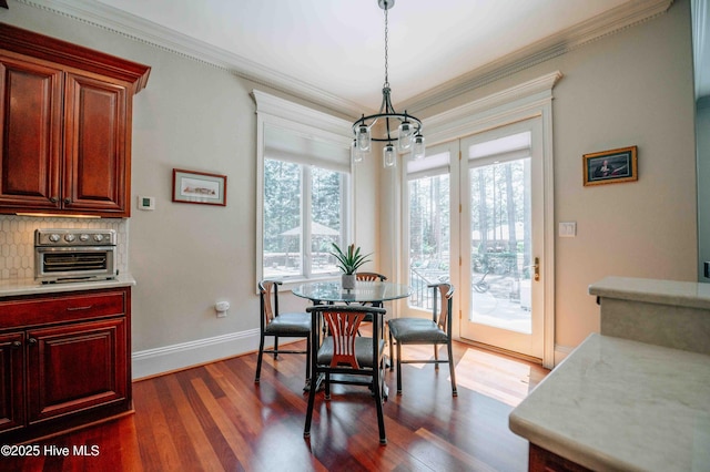 dining area featuring crown molding, a toaster, baseboards, dark wood-style floors, and a chandelier