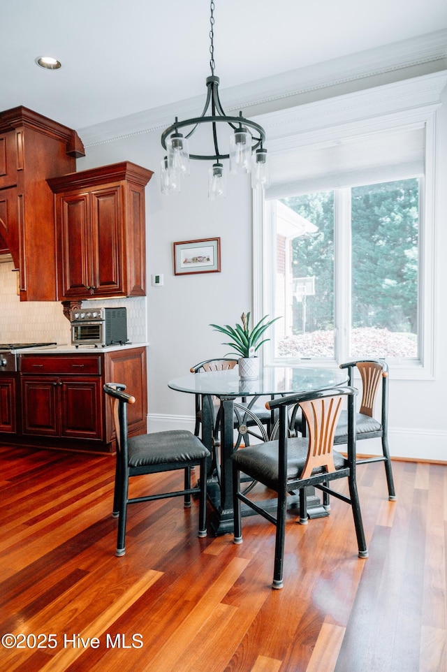 dining room with crown molding, baseboards, wood finished floors, and a notable chandelier