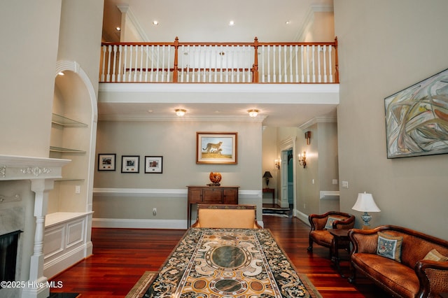 living area featuring crown molding, dark wood finished floors, and a towering ceiling