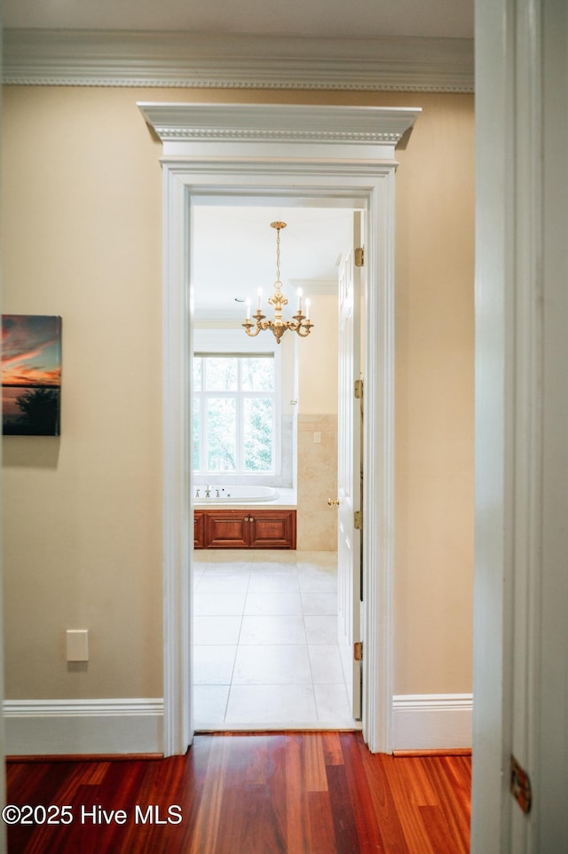 hallway with crown molding, baseboards, an inviting chandelier, and light wood-type flooring
