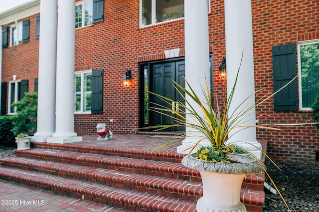 property entrance with a porch and brick siding