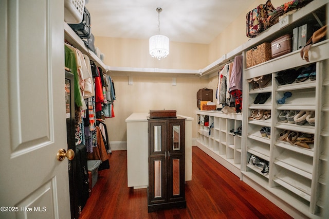 walk in closet featuring dark wood finished floors and a notable chandelier