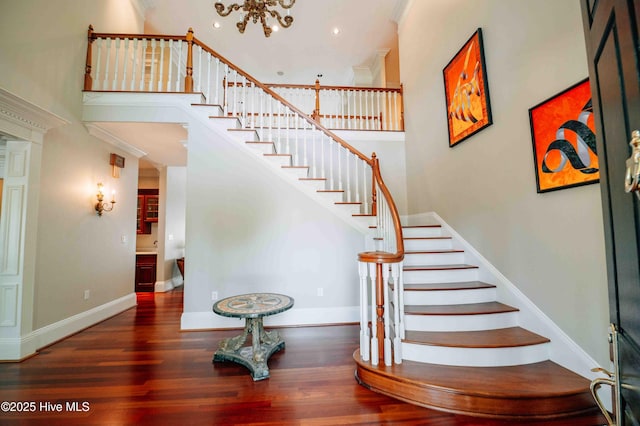 stairs featuring crown molding, baseboards, a high ceiling, and wood finished floors