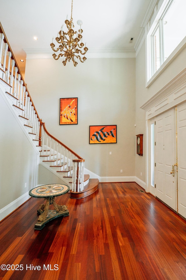 entrance foyer featuring baseboards, crown molding, a chandelier, and stairway
