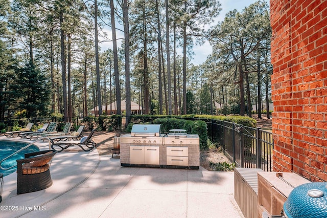 view of patio / terrace with area for grilling, exterior kitchen, fence, and a swimming pool