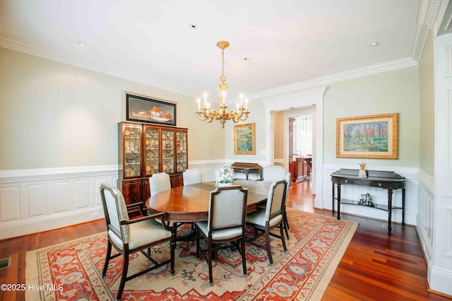 dining area with crown molding, a chandelier, and wood finished floors