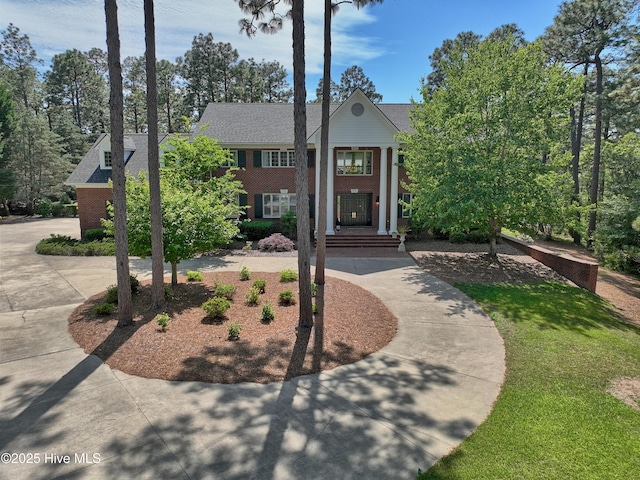 neoclassical / greek revival house with brick siding and a shingled roof