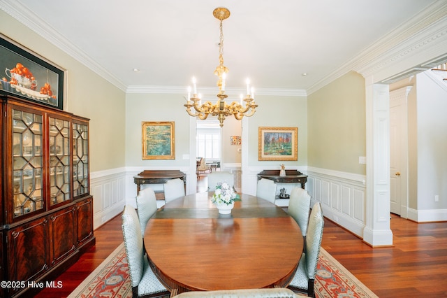 dining space with ornamental molding, wood finished floors, a notable chandelier, and a wainscoted wall