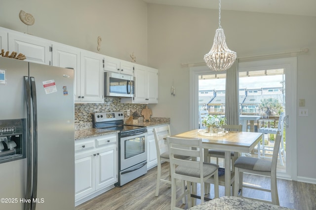 1774 New River Inlet Rd Unit 5, North Topsail Beach, NC 28460 - kitchen featuring backsplash, stainless steel appliances, a notable chandelier, and white cabinetry
