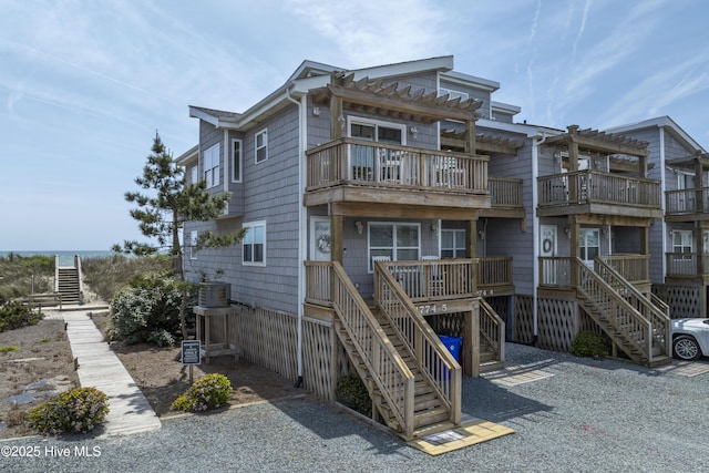 1774 New River Inlet Rd Unit 5, North Topsail Beach, NC 28460 - view of front of property with stairs, central AC unit, a balcony, and a pergola