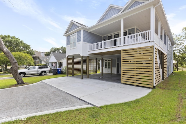 rear view of house featuring concrete driveway, a lawn, and a carport