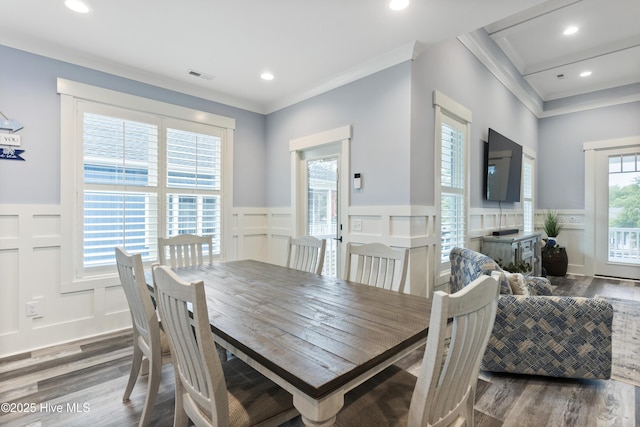 dining room with wainscoting, a decorative wall, and wood finished floors