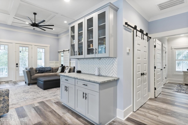 interior space featuring ceiling fan, visible vents, a barn door, and wood finished floors