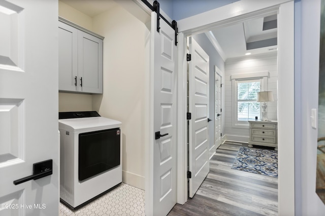 clothes washing area with washer / clothes dryer, crown molding, cabinet space, a barn door, and wood finished floors