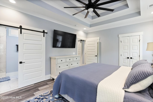 bedroom featuring a raised ceiling, recessed lighting, a barn door, and visible vents