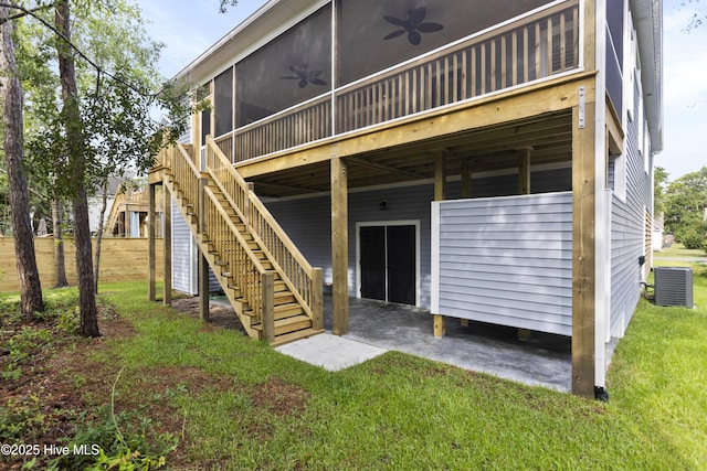 rear view of property featuring ceiling fan, a sunroom, stairs, a patio area, and a lawn