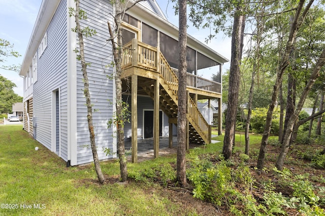 back of house featuring a lawn, stairs, a sunroom, and a wooden deck