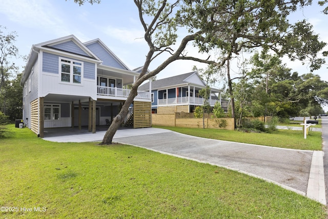 view of front facade featuring a front lawn, covered porch, driveway, and a carport